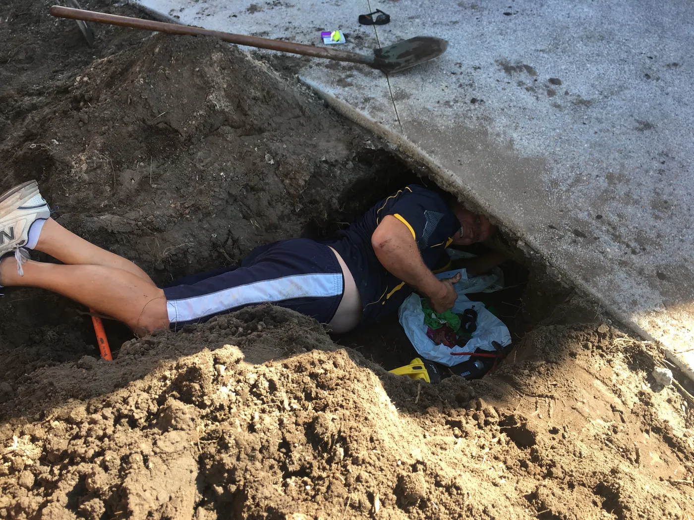 Plumber repairing a burst pipe beneath a concrete path on the Gold Coast